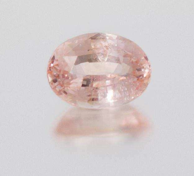 Lot 233 A 6.56 Carat Oval Mixed Cut Padparadscha Sapphire, measuring approximately 13.04 x 9.69 x 6.01 mm.