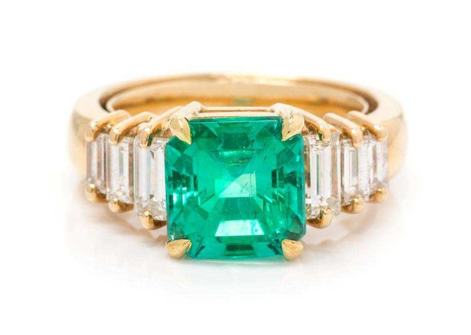 Lot 346 An 18 Karat Yellow Gold, Emerald and Diamond Ring, containing one octagonal step cut emerald weighing approximately 3.09 carats and six baguette cut diamonds weighing approximately 1.