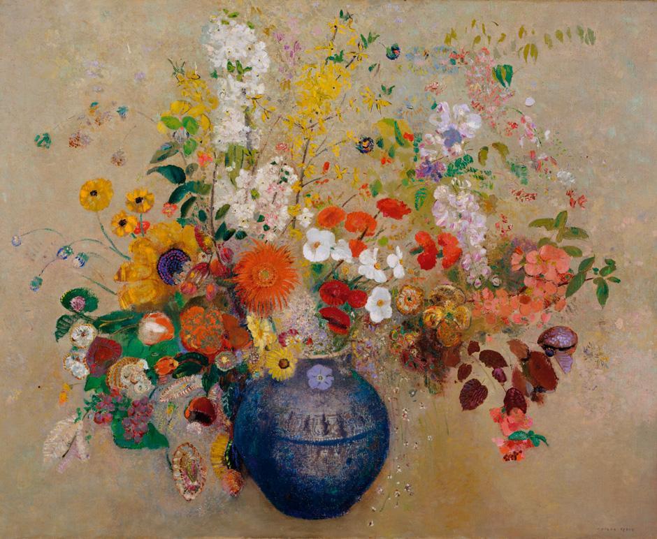 The vase is a dull blue color contrasting with high saturated yellow and orange flowers flowing out of the vase.