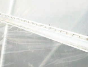 Photo shows the second layer of film secured to the single U-channel at an end rafter. Note the two spring sections in the channel; one for each of the film layers.