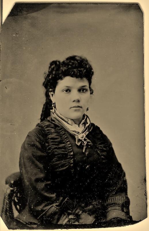 The tintype without the envelope is 3 ¾ inches high and 2 ½ inches wide. Description: Tintype of a young woman wearing a dark colored dress. She is wearing a locket and large drop earrings.