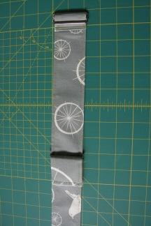 like.) Slide one of the metal loops onto one of the strap tabs, fold the tab in half raw edges together and