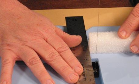 Lay a metal ruler vertically across the base of the Foam Cutter, lining it up 1/4" from the wire cutting element.