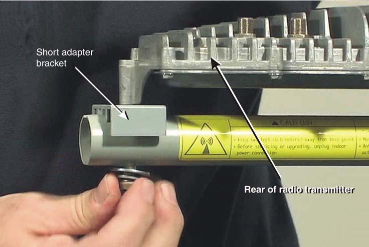 8. Place the short adapter bracket in position near the end of the feed support arm and lower the radio onto it as shown in Figure 19. Figure 19: Securing the rear of the radio assembly 9.