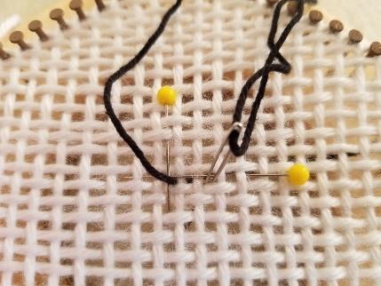 Bring the needle and yarn up where the two pins intersect.