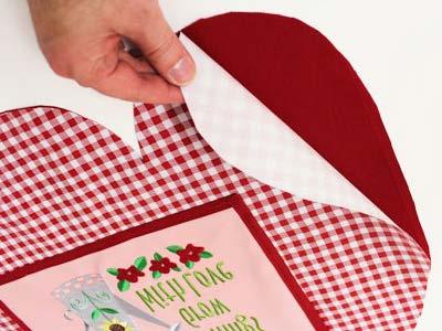 Trim the accent, cutting around the top of the apron fabric shape. Add bias tape. Wrap it around the bottom edge of the accent piece. Trim the tape, leaving about 1/2" excess on each end.