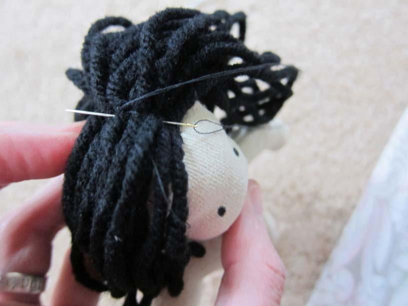 Remove the stabilizer and backstitch the hair onto the doll's