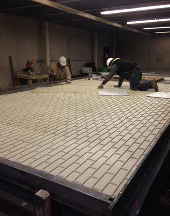 Following the layouts on the architectural and engineering drawings that are specific to every panel, workers place the plastic formliner on the rotating steel tables prior to concrete placement.