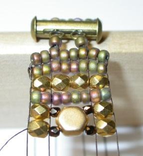 Pass the weaving thread under the warps and slide the seed beads into