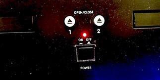 The On and Off button is located at the bottom center of the unit, right next to the 2 eject buttons.