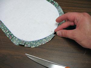 Cut 1/2 inch slits around the curved edges of the fabric about