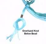 Tie an Overhand knot just below the bead, with no gap. Tighten it firmly and push the bead against it.