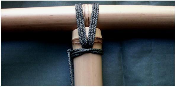 Here is the completed joint, showing how lashings are made on both sides of the cross-pole node. The lashing is finished with a clove hitch around the upright, and a square knot.