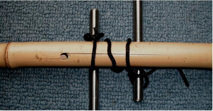 Slip one bowline loop over the end of one lever, then lay the bamboo across the lever.