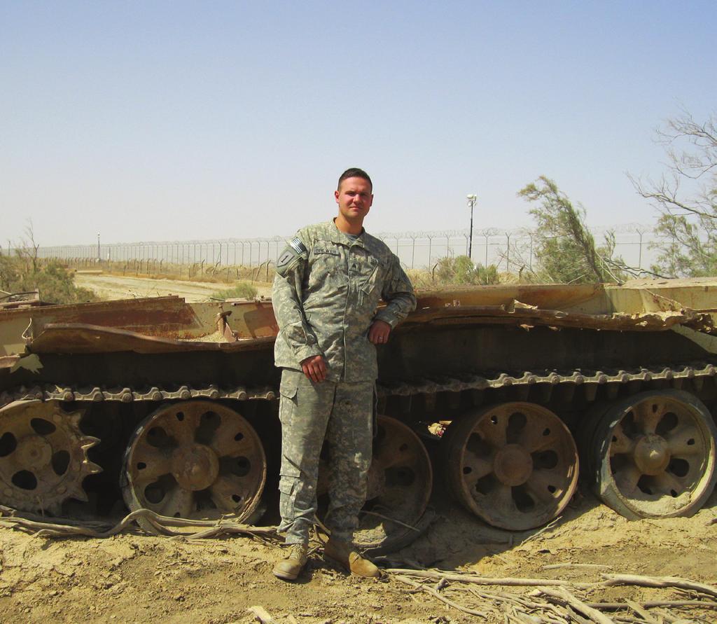 Brewer posing next to the bottom half of an Iraqi tank. the yelling might as well have been blood in the water. While there, Brewer hated every second.