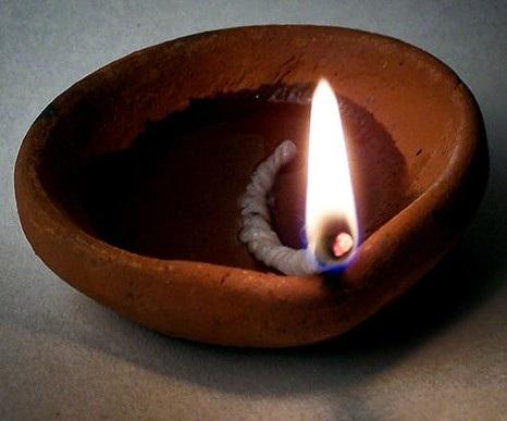 Mama said "A diya is an oil lamp made of clay. We pour oil into the clay bowl and make a wick from cotton. When we light the oil soaked cotton, the flame lights up the area around. It is very pretty.