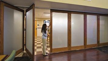 Frameless OPERABLE GLASSWALL consists of glass panels mechanically fastened to horizontal top and bottom rails.