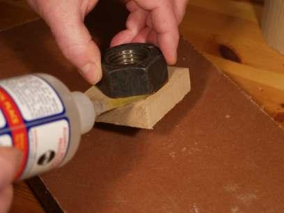 After rubbing one side of a nut on some sandpaper to give the glue a key, it was simply superglued to a small block of MDF.