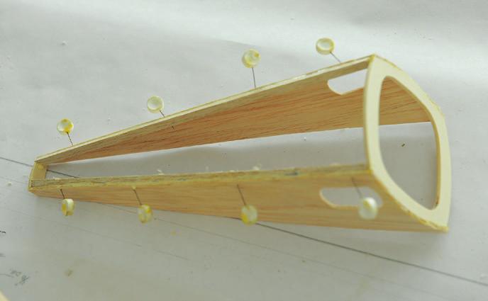 Use elastics to hold them in place around the outside of the fuselage. Take the remaining pieces of the 3 / 16 x 3 / 8 balsa strips, and cut them in half lengthwise, with your scroll saw set at 30º.