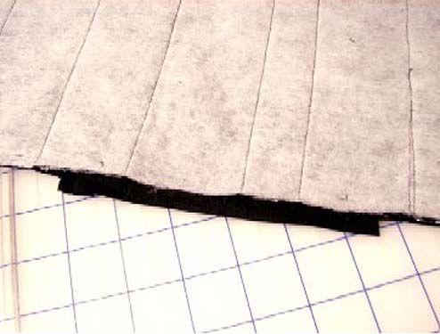 Change your top and bobbin thread to a black cotton construction thread; sew the strips to the background fabric. 8.