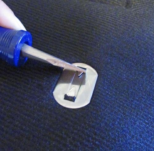 With a flat head screwdriver, fold both prongs down towards the center so they lay completely flat within the
