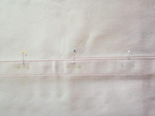 On the back panel with the 2" hem, mark for three centered 1" buttonholes.