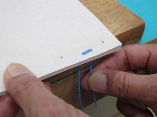 Pull the both ends of the paper string through two holes for inner binding.