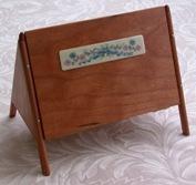is an exquisitely handcrafted adaptation of an antique sewing box. The box is made of fine cherry wood and measures approx. 6 ¼ wide x 4 ¾ tall (with legs) and 3 ½ deep.