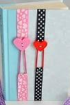 Ribbon Bookmarks Decorative Ribbon at least 1/2 in. wide Elastic hair Bands Decorative Buttons Scissors Needle & Thread or Sewing machine 1. Cut the ribbon into 18 inch strips 2.