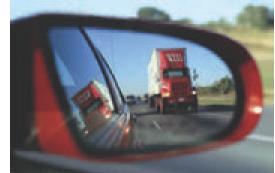 An automobile rearview mirror shows an image of a truck located