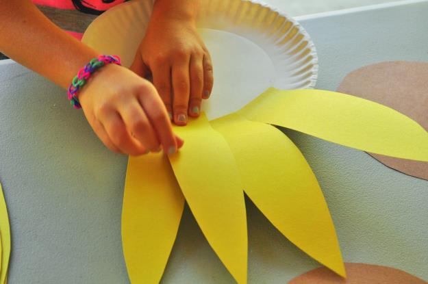Help the child, paste the petals on the edges of the paper plate as shown in the image. 4.