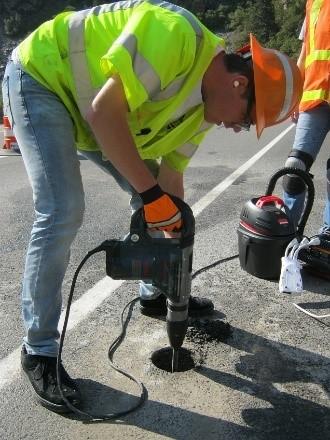 To remove the final layers of concrete above the rebar, a hammer drill is used to drill through several inches of concrete, shown in Figure 15.
