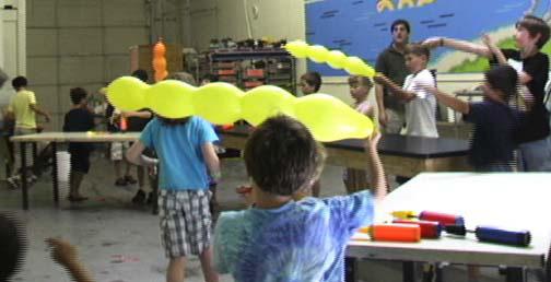 [Students use various techniques to propel their long thin balloons toward the pirate ship. If one successfully lands on the ship, the Instructor lowers it so the student can retrieve it.