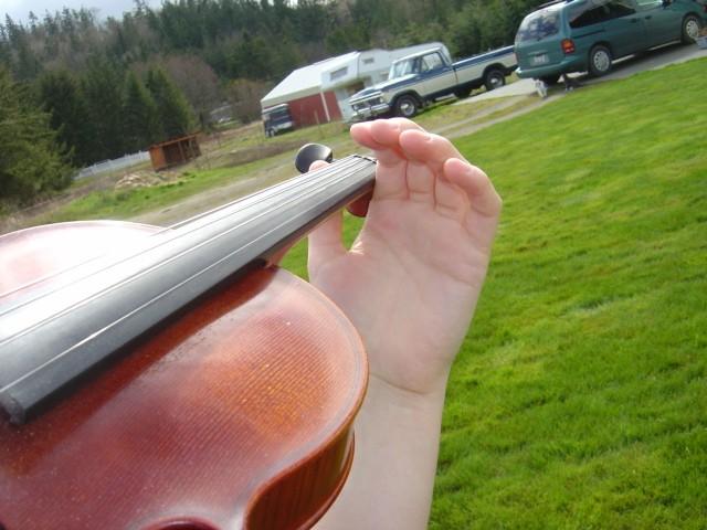 After sliding a few times, come to a stop near the scroll of the violin. Notice the open space in Christina's hand? That's good! Do you see the space between her thumb and the violin neck?