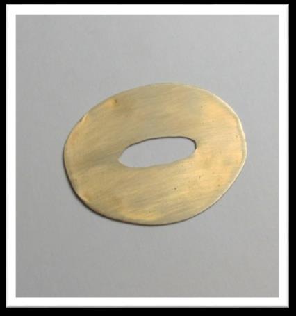 Using scissors, trim the circle to create a more oval shape around the oval center. Cut out the center of the pattern. Trace the shape onto the brass.