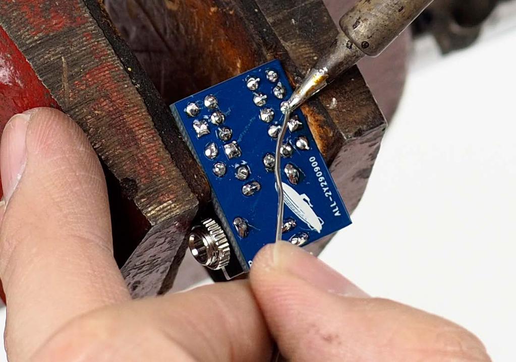 Tack one pin on the end of the row down with solder while
