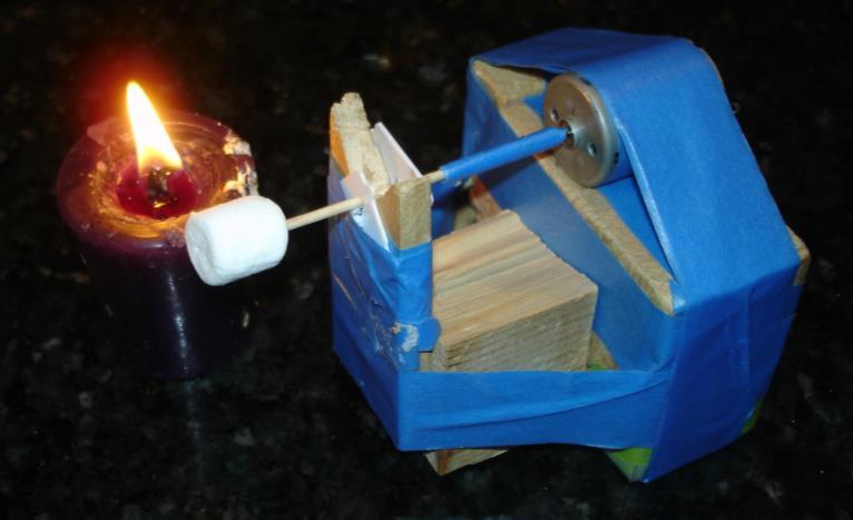A wooden stick was connected to the shaft output of the motor. A marshmallow is held at the end of the stick.