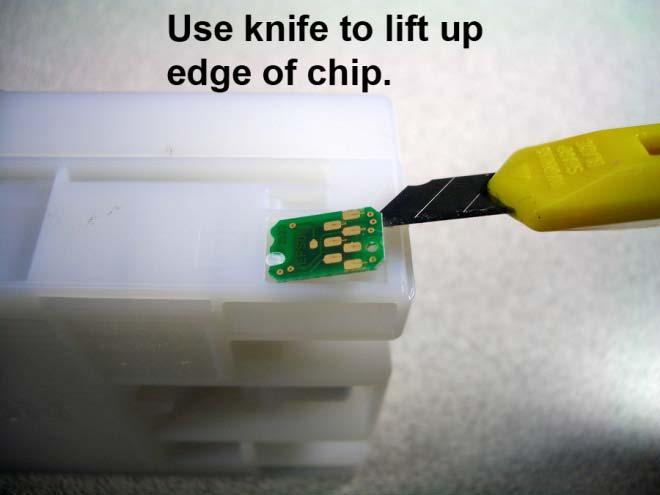 Once you have trimmed off the top of the plastic stud, use the knife to lift up the edge of the chip. The chip can now be pulled off the original cartridge.