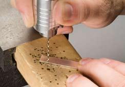 Support the strip on your bench pin or a wooden block. Insert the drill bit into a flex shaft, and apply beeswax or lubricant to the bit.