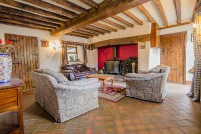 SITTING ROOM Forming part of the original house with a heavy beamed ceiling, there is a substantial inglenook fireplace with a wide beam, a raised quarry tiled hearth and a large free standing