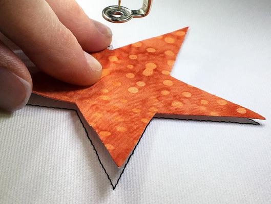 With the paper still stuck to the right side of the applique fabric, spray the wrong side of the fabric with temporary spray adhesive. 7.