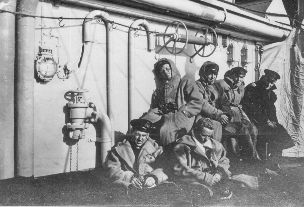 Officers taking a break aboard HMS Falmouth, including Sub-lieutenant Pears (seated on stowage bin, at left). John MacDonald especially through the media.
