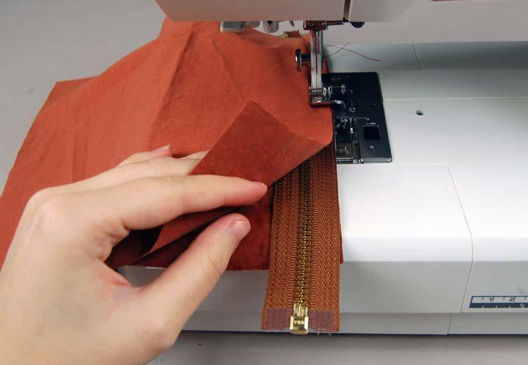 2 To begin constructing the bag flap, start by layering your zipper between the lower left bag flap piece and its corresponding lining piece.