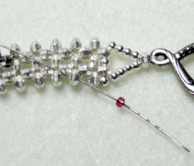 Put one size 11 seed bead on the thread. Go through the spacer directly next to the spacer where your thread is coming out.