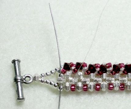Take the needle and go up through the second spacer to the right of the clasp loop.