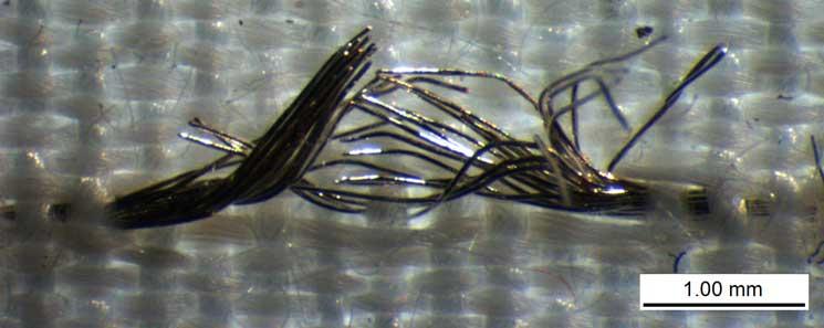 Figure 2.11: Magnification of the failed conductive yarn that is marked (*) in figure 2.10. Most filaments in the conductive yarn fail at the same location, as can be seen in figure 2.11. The failure is localized at the center of the float, where one weft yarn passes over the conductive yarn (see also figure 2.