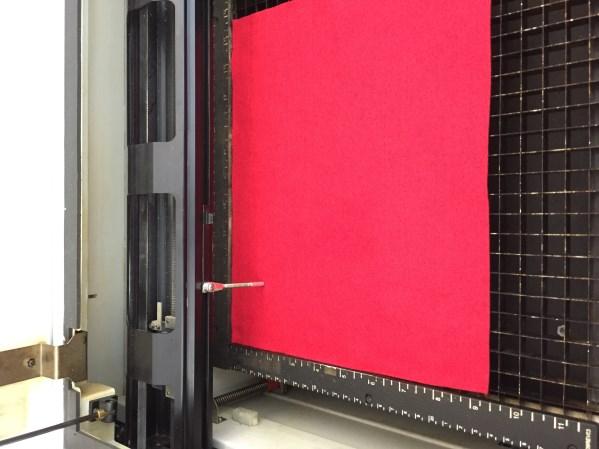 After opening the lid of the engraver and placing your fabric flush against the top right corner of the grid, press the Focus button. 9.