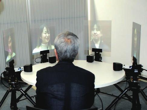 Photo 6. Visitor experiencing a video conference with dynamically moving displays. Photo 7. Visitors watching research presentation on infant s vocabulary spurt onset.
