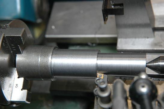 Line up a the left edge of a parting tool with the end of the bar and then move the saddle down the lathe bed by 1 plus the width of the parting tool.