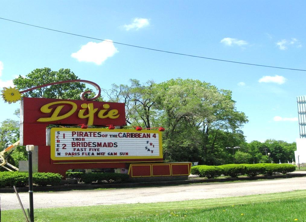 Drive in theater sign close to road; showing proximity to theater screen at far right.